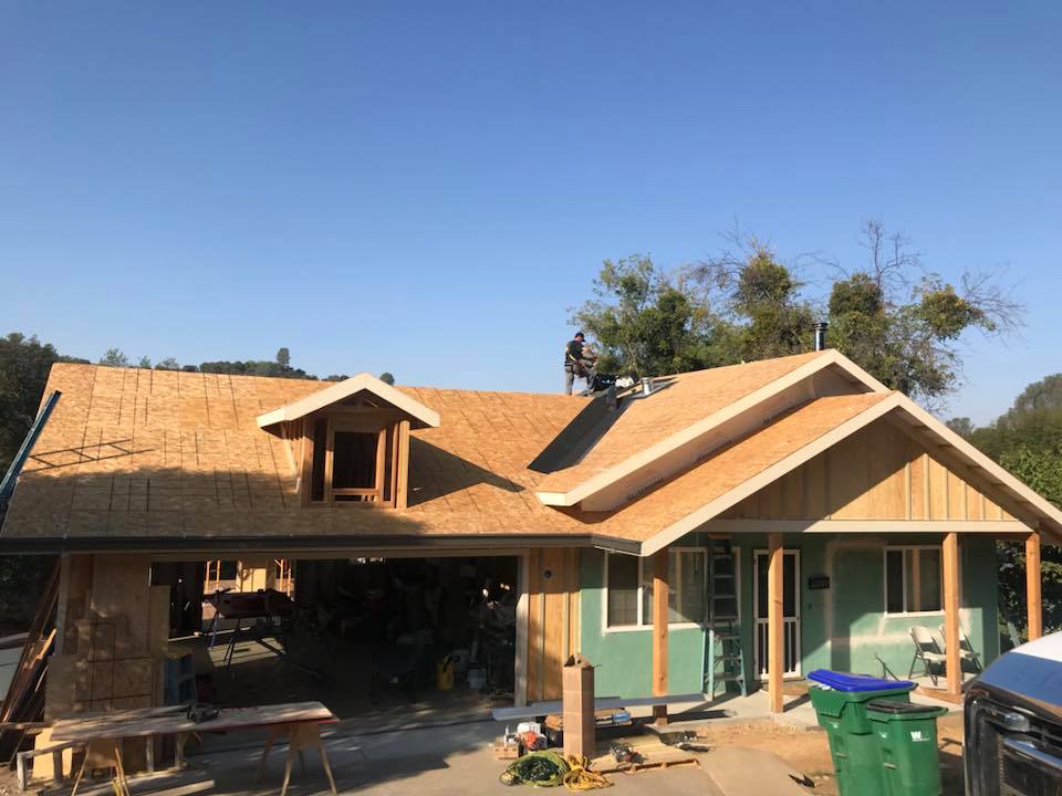 new roof being installed by kelly roofing contractors is in the final stages of installation on a beautiful blue day in Salida, California residential suburb