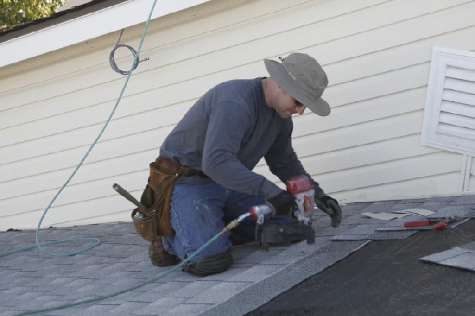 shingles being applied to roof of a residential house by kelly roofing contractor